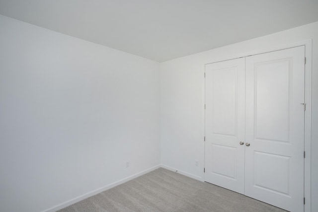 unfurnished bedroom with light carpet and a closet