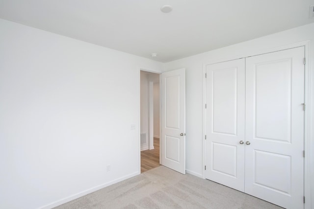 unfurnished bedroom featuring light colored carpet and a closet