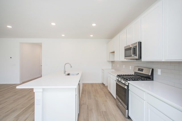 kitchen with white cabinetry, stainless steel appliances, sink, and an island with sink