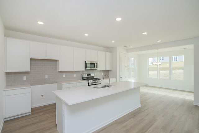 kitchen featuring sink, a kitchen island with sink, white cabinetry, stainless steel appliances, and light wood-type flooring