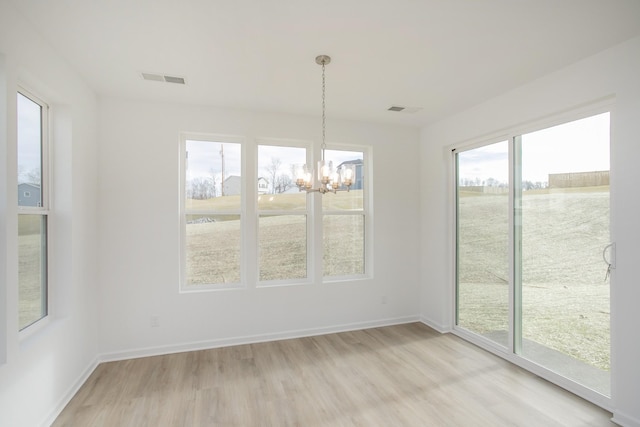 unfurnished dining area featuring a notable chandelier and light hardwood / wood-style floors