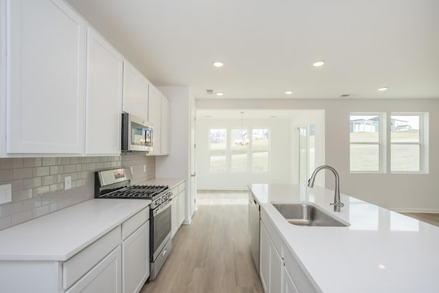 kitchen with tasteful backsplash, white cabinetry, appliances with stainless steel finishes, and sink