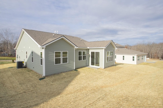 rear view of house with central AC and a lawn