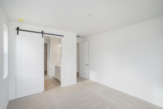 unfurnished bedroom with a barn door and light colored carpet