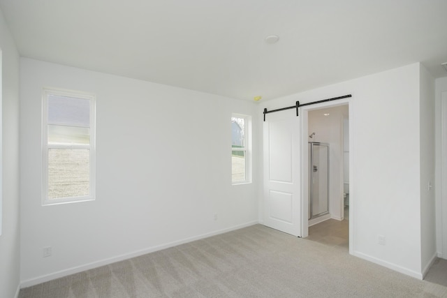 unfurnished room with light colored carpet and a barn door