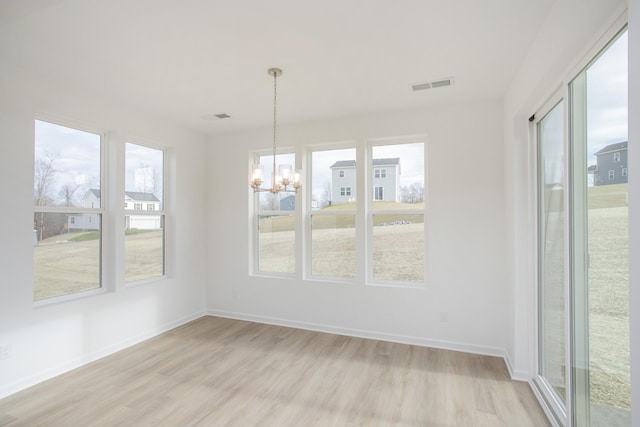 unfurnished dining area with a healthy amount of sunlight, a chandelier, and light hardwood / wood-style floors