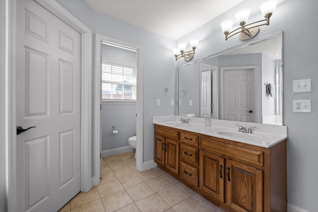 bathroom with tile patterned flooring, vanity, a chandelier, and toilet