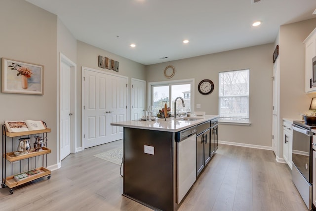 kitchen featuring appliances with stainless steel finishes, sink, a center island with sink, and light hardwood / wood-style floors