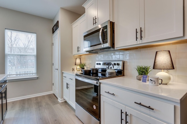 kitchen featuring decorative backsplash, light hardwood / wood-style floors, white cabinets, and appliances with stainless steel finishes