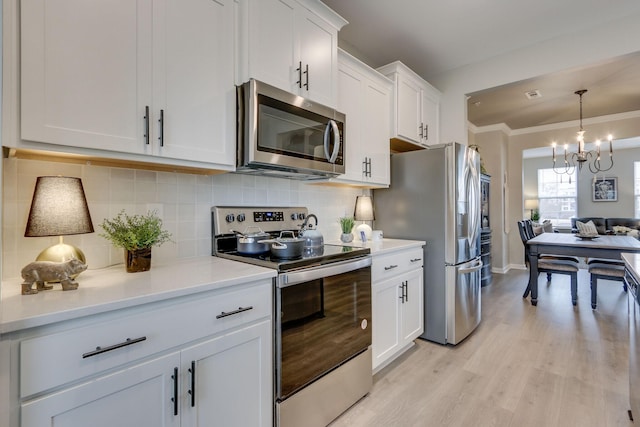 kitchen featuring white cabinetry, backsplash, stainless steel appliances, crown molding, and light hardwood / wood-style flooring