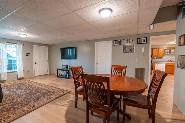 dining area featuring a drop ceiling and light hardwood / wood-style floors