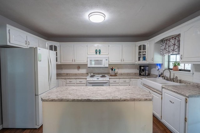 kitchen featuring dark wood-type flooring, sink, white cabinetry, a center island, and white appliances