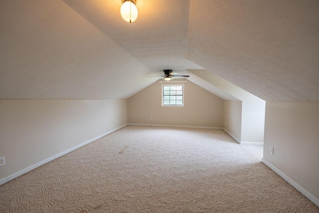 additional living space with vaulted ceiling, carpet flooring, and a textured ceiling