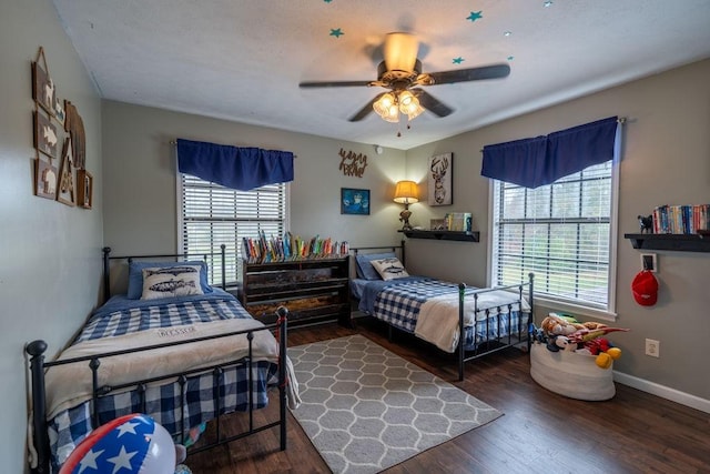 bedroom with multiple windows, dark hardwood / wood-style floors, and ceiling fan