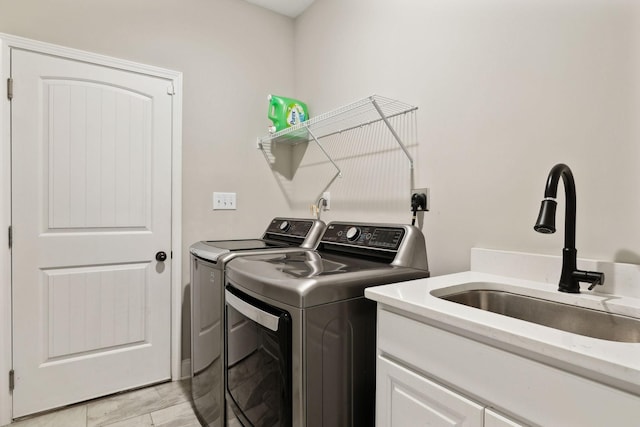 washroom with cabinets, independent washer and dryer, and sink