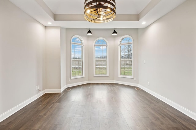 empty room featuring dark wood-type flooring and a tray ceiling