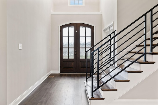 entrance foyer featuring a high ceiling, plenty of natural light, dark wood-type flooring, and french doors