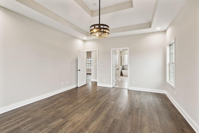 empty room featuring dark wood-type flooring and a raised ceiling