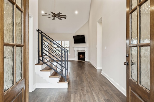 entrance foyer with dark wood-type flooring, a high end fireplace, ceiling fan, and vaulted ceiling