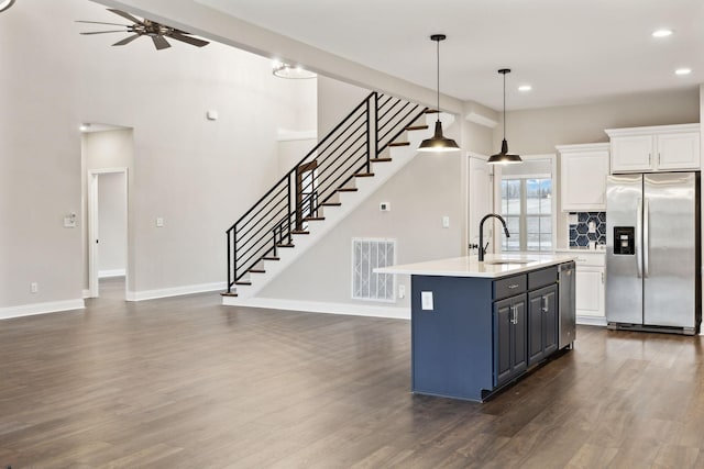 kitchen featuring appliances with stainless steel finishes, white cabinetry, an island with sink, sink, and hanging light fixtures