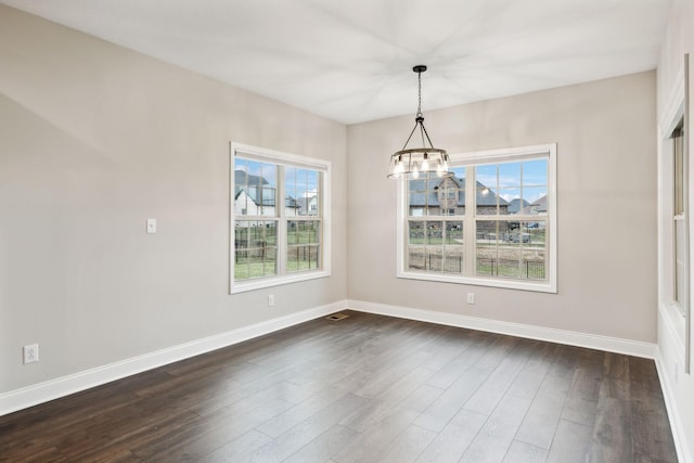 unfurnished dining area with an inviting chandelier and dark hardwood / wood-style flooring