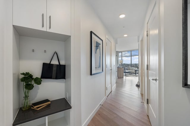 hall with recessed lighting, light wood-type flooring, baseboards, and expansive windows