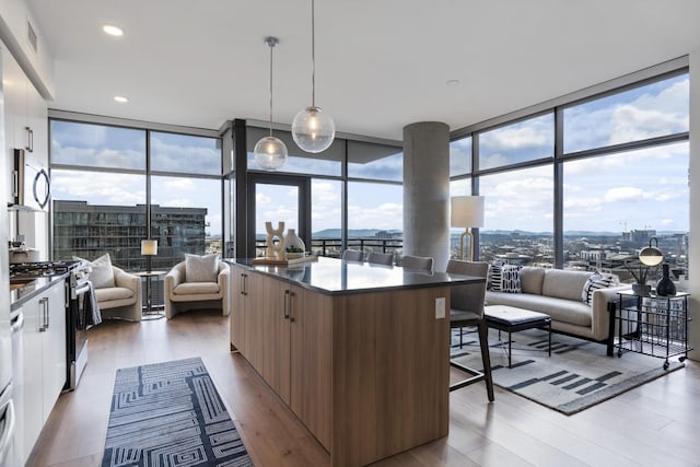 kitchen featuring hanging light fixtures, floor to ceiling windows, appliances with stainless steel finishes, and white cabinets