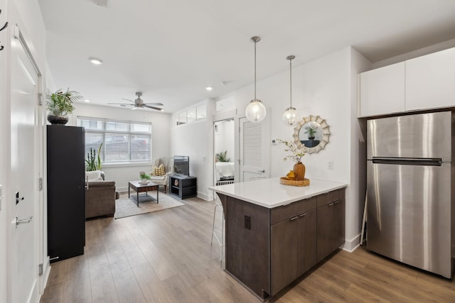 kitchen with dark brown cabinetry, hardwood / wood-style floors, stainless steel refrigerator, and white cabinets