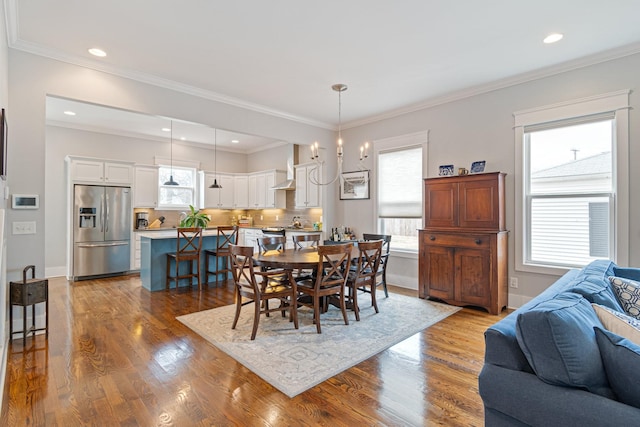 dining area with ornamental molding, a wealth of natural light, and light hardwood / wood-style floors