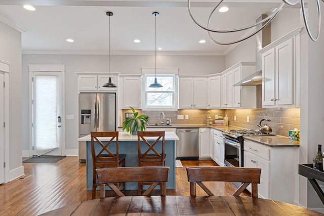 kitchen featuring white cabinetry, appliances with stainless steel finishes, decorative light fixtures, and crown molding