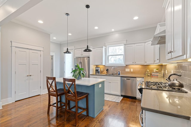 kitchen with sink, white cabinetry, hanging light fixtures, appliances with stainless steel finishes, and a kitchen island