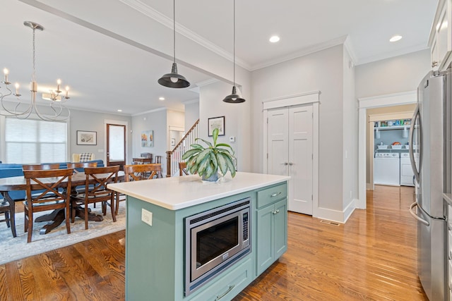 kitchen with crown molding, appliances with stainless steel finishes, a kitchen island, pendant lighting, and light hardwood / wood-style floors