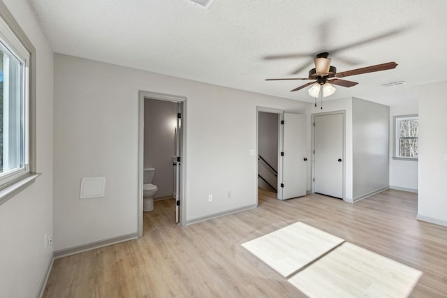 unfurnished bedroom featuring ceiling fan, a textured ceiling, light hardwood / wood-style floors, and ensuite bath