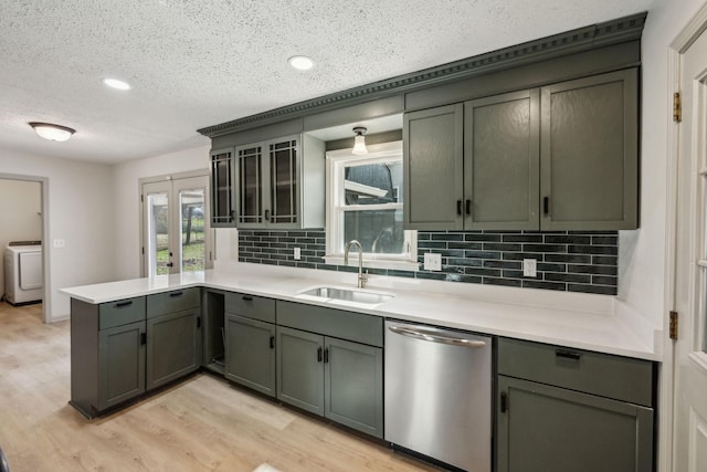 kitchen featuring dishwasher, washer / dryer, sink, decorative backsplash, and light wood-type flooring