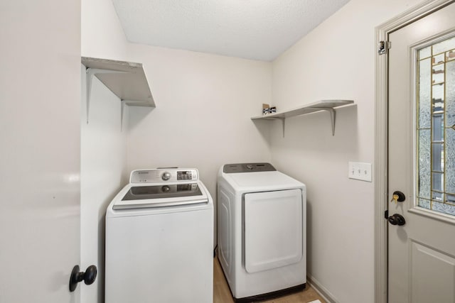 clothes washing area with light wood-type flooring, washing machine and clothes dryer, and a textured ceiling