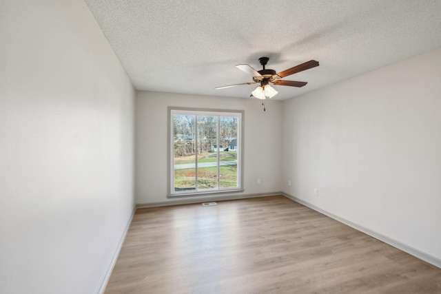 spare room with ceiling fan, a textured ceiling, and light wood-type flooring