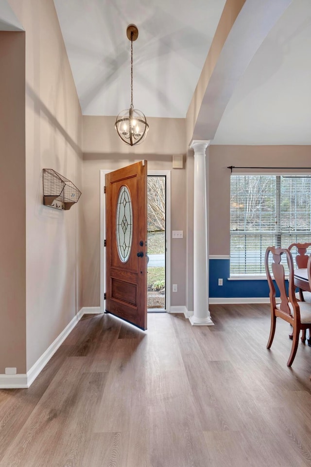 foyer entrance featuring hardwood / wood-style flooring, lofted ceiling, an inviting chandelier, and decorative columns