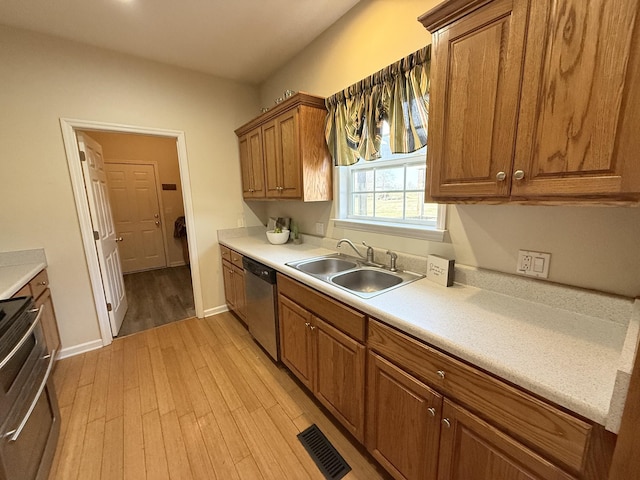 kitchen with sink, stove, light hardwood / wood-style floors, decorative light fixtures, and stainless steel dishwasher