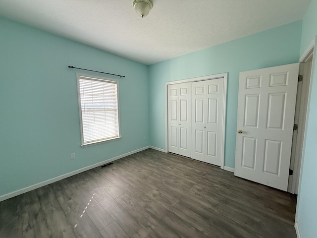 unfurnished bedroom with dark hardwood / wood-style floors, a closet, and a textured ceiling