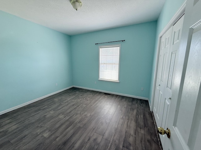 unfurnished bedroom with dark hardwood / wood-style floors, a closet, and a textured ceiling