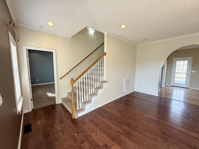 interior space featuring ornamental molding, dark wood-type flooring, and a textured ceiling