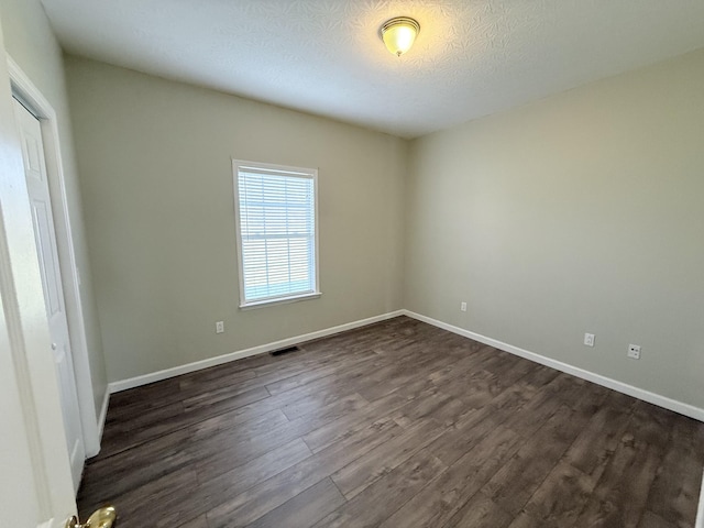 empty room featuring dark hardwood / wood-style floors and a textured ceiling