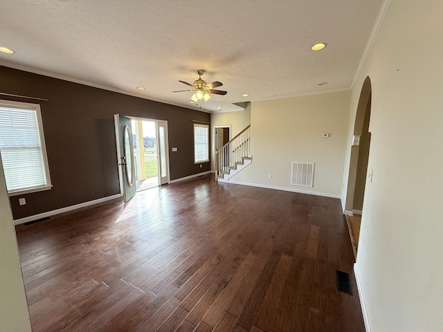 unfurnished living room featuring ceiling fan, dark wood-type flooring, ornamental molding, and a textured ceiling