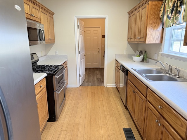 kitchen with appliances with stainless steel finishes, light hardwood / wood-style floors, and sink