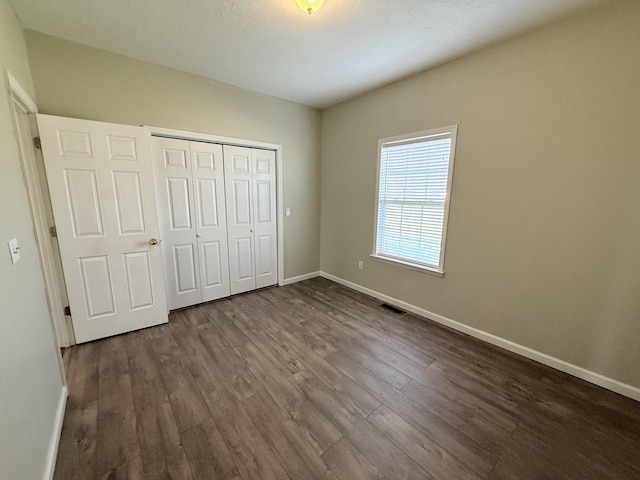 unfurnished bedroom with dark hardwood / wood-style floors and a closet