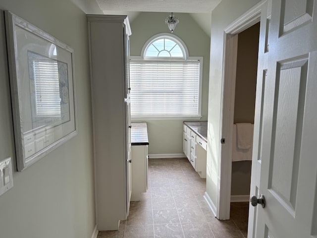 bathroom with tile patterned flooring, vanity, and lofted ceiling