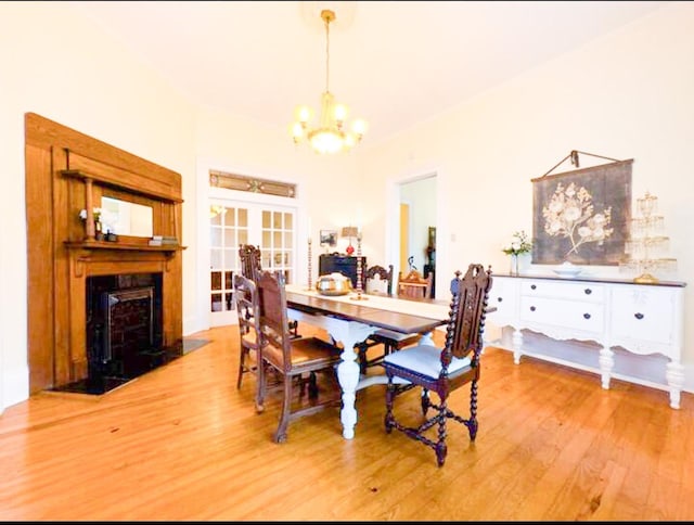 dining space featuring wood-type flooring, a notable chandelier, and french doors