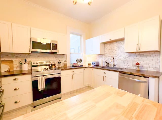 kitchen featuring sink, tasteful backsplash, wooden counters, stainless steel appliances, and white cabinets