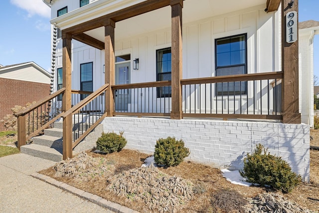 view of exterior entry featuring a porch and board and batten siding