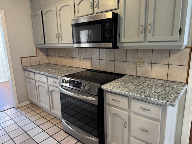 kitchen with light tile patterned flooring, stainless steel appliances, and decorative backsplash